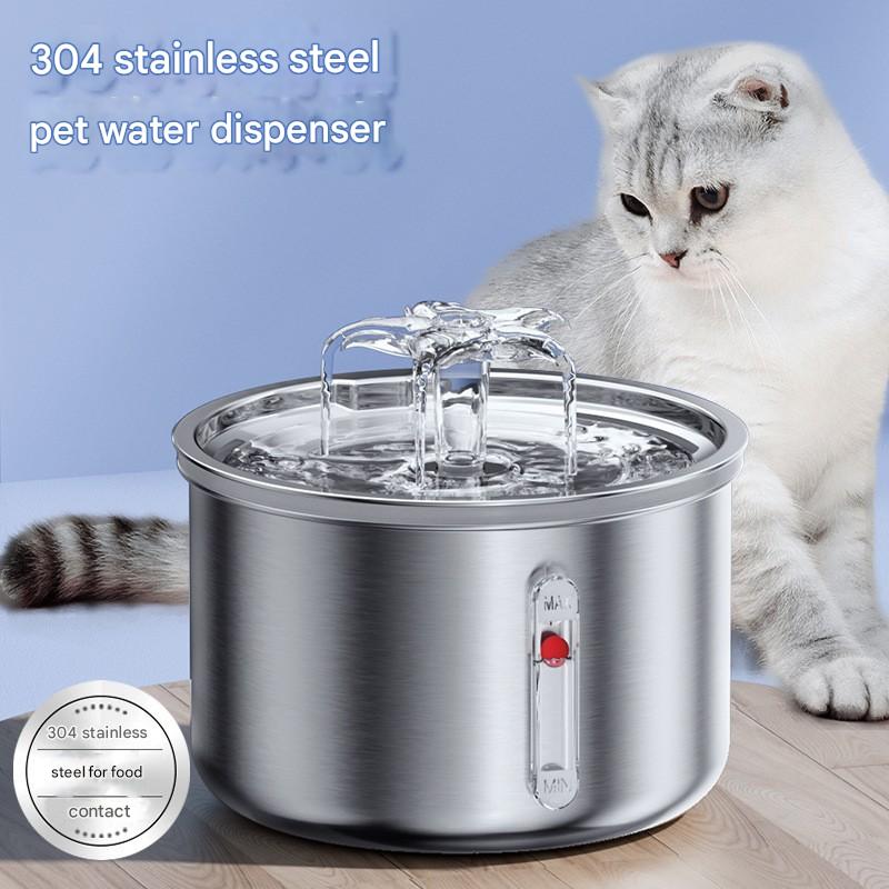 Stainless steel pet water dispenser with a cat sitting next to it on a wooden floor.