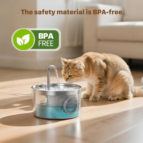 A ginger cat drinking fresh water from a transparent, BPA-free stainless steel cat fountain dispenser indoors.
