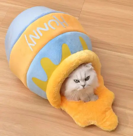 Cat inside a plush honeycomb toy on a wooden floor.