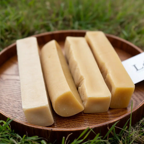Long lasting dog treats made by yak cheese in plate with a grassy background.