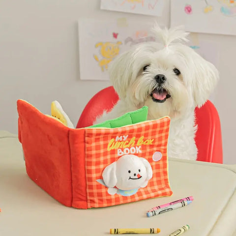Small white dog with an interactive pet book and crayons on a table