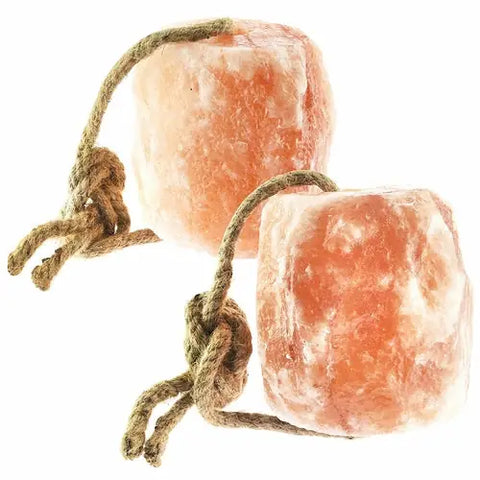 Two pink Himalayan salt lick blocks for small pets suspended with rope.