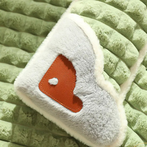 White plush toy with brown patch on green textured pet bed.