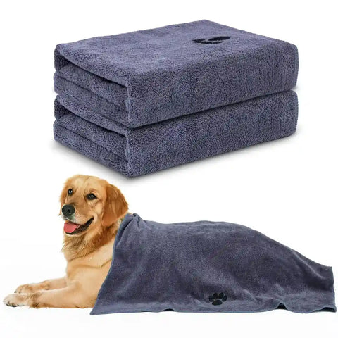 A 2-pack set of folded dark gray microfiber pet towels featuring a black paw print logo, pictured next to a Golden Retriever lying down under one of the towels.