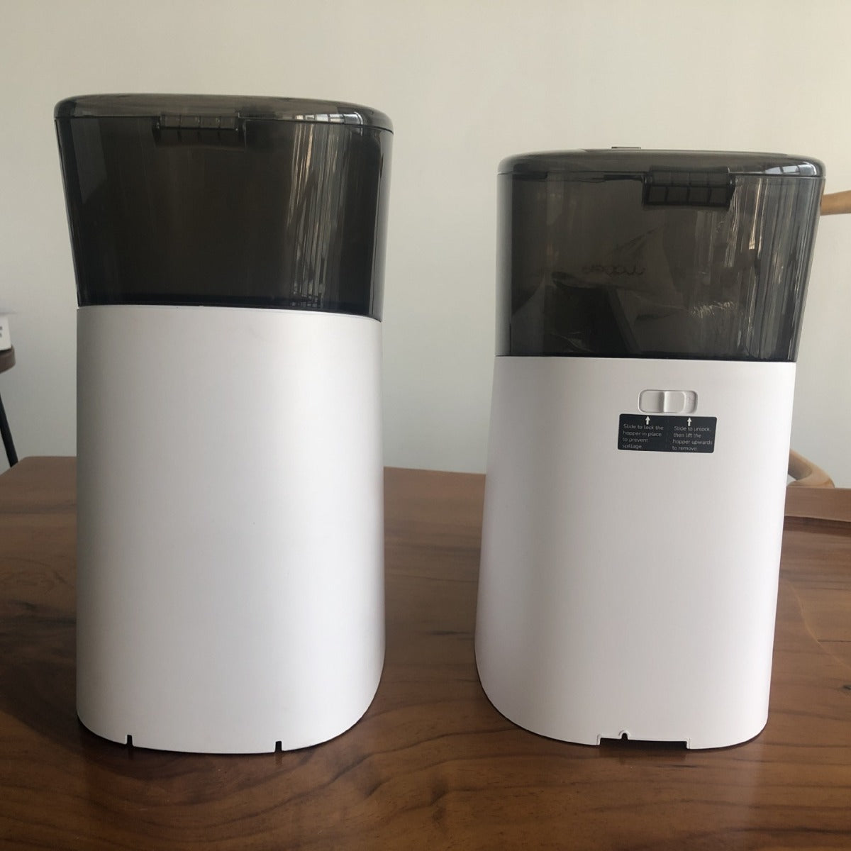 Two auto dog feeder with black lids on a wooden surface.