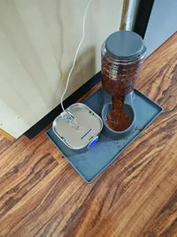 Gravity pet food dispenser and a stainless steel automatic water fountain neatly placed together on a compact gray silicone floor mat.