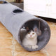 Cat inside a gray tunnel toy on a wooden floor.