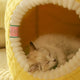 Cat lying inside a yellow pet house with a soft interior.