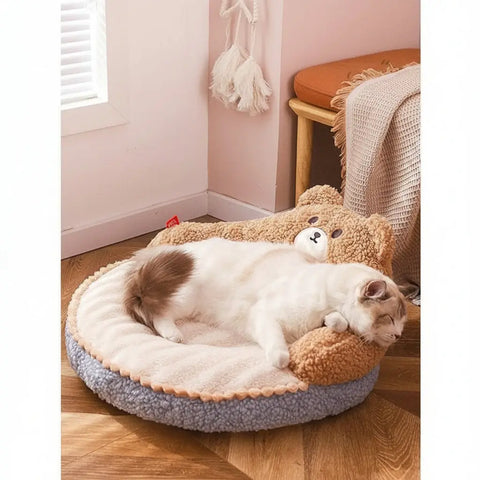 Cat lying on plush pet bed with bear design in cozy room.