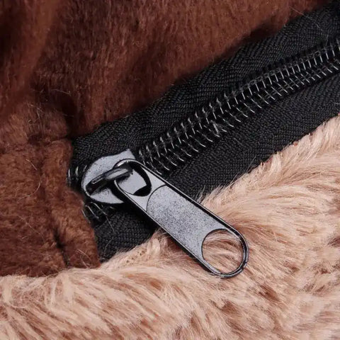Close-up of a black zipper on a brown and beige fur surface.