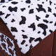 Close-up of brown fabric with white border featuring black abstract shapes.