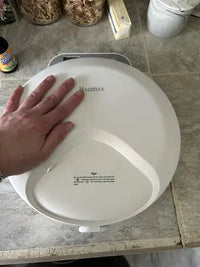 Customer review close-up photo showing top lid and safety lock of white Bsemax automatic pet feeder on countertop