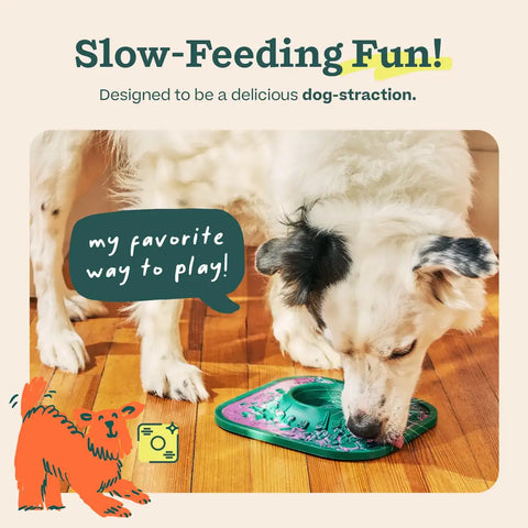 Black and white dog enjoying spreadable treat on a green Woof LickMat on hardwood floor.