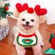 Dog wearing festive outfit with red heart-shaped ears and bib.