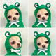 Dog wearing green frog costume with large eyes and white bow tie.