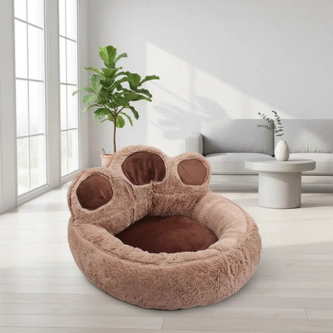 Fluffy paw-shaped pet bed on wooden floor with decorative vases.