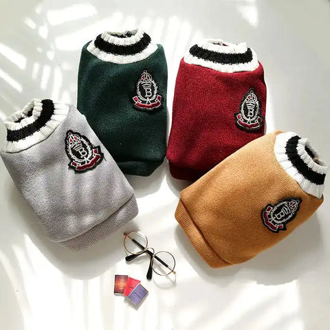 Four dog sweaters in gray, green, red, and brown with a logo on a white surface.
