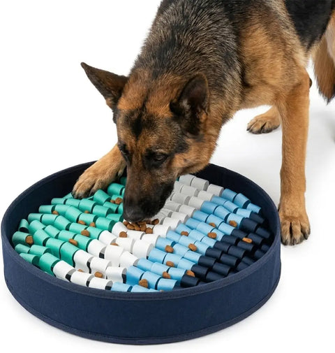 German Shepherd foraging for dry food inside a round navy blue snuffle mat with teal, white, and blue fabric loops.