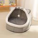 Gray pet bed with cat ears and a hanging ball on light-colored floor.
