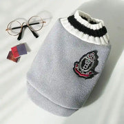 Gray sweater with a logo patch on light gray background.
