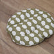 Green cushion with white floral pattern on a wooden floor