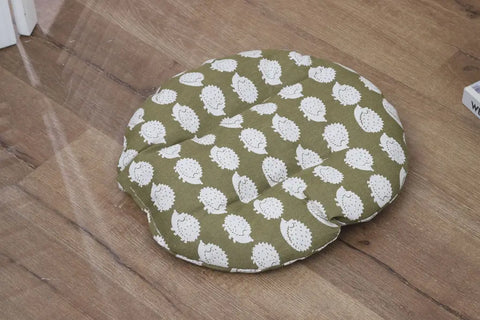 Green cushion with white floral pattern on a wooden floor