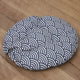 Green cushion with white floral pattern on wooden floor.