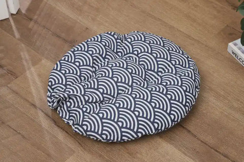 Green cushion with white floral pattern on wooden floor.