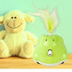 Green electronic toy with feather attachment next to a plush lamb