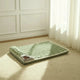 Green pet bed on carpeted floor with wooden crate and decorative items.