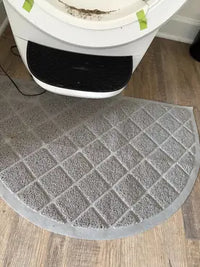 Half-circle grey cat litter trapping mat positioned in front of an automatic self-cleaning litter box