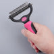 Hand holding pink and black pet grooming tool against gray background.