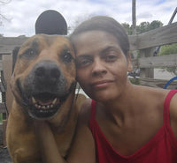 Smiling customer taking selfie outdoors with happy brown Boxer Pitbull mix dog beside her