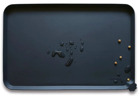 Hoki Found Dark Cedar charcoal black silicone dog bowl mat with water droplets and pet kibble.