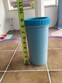 A yellow tape measure showing the height and dimensions of a large blue silicone dog paw cleaner cup.