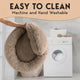 Person holding a flexible plush dog bed in front of a washing machine showing washable feature