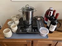 Large gray silicone protective countertop mat used as a coffee and beverage station coaster with mugs, bottles, and a hot pot.