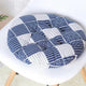 Natural woven cat bed with rope handles and soft cushion.