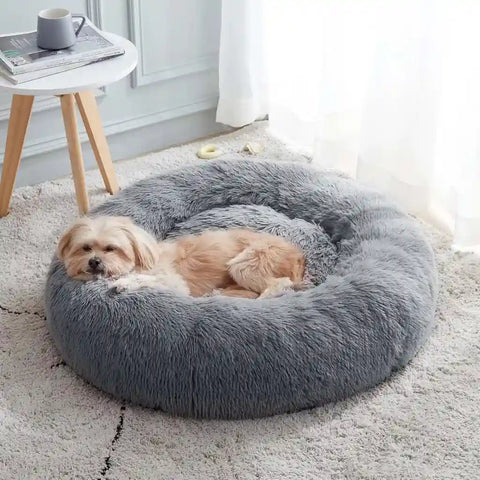 Small dog sleeping soundly in a cozy navy grey calming donut pet bed