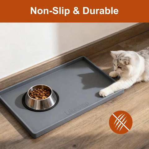 Fluffy cat playing near a stainless steel bowl resting securely on an anti-slip and scratch-resistant grey silicone feeding mat.