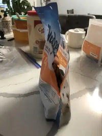 Side profile of a Nudges dog treats bag sitting on a white marble kitchen counter