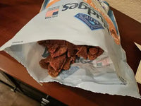 An open bag of Nudges Jerky Cuts showing several pieces of heart-shaped chicken and duck dog treats.