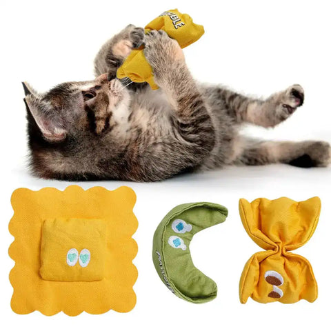 A brown tabby kitten rolling on its back playing with a yellow pasta-shaped plush toy, featured alongside three Italian pasta-themed catnip toys: ravioli, penne, and farfalle.