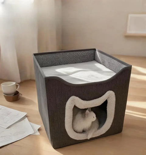 Pet bed with a cat inside on wooden floor with cup and papers.