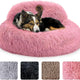 Medium dog relaxing in a bright pink fuzzy donut dog bed with raised bolster