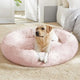 Golden Retriever lying relaxed on a soft pink plush donut dog bed