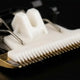 Close-up macro view of a professional dog grooming clipper blade featuring a white ceramic moving blade and a gold titanium fixed blade.

