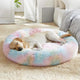 Golden Retriever sleeping peacefully on a rainbow tie-dye fluffy donut dog bed
