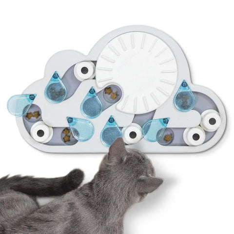 Grey cat interacting with a rainy day cloud-shaped treat puzzle featuring blue raindrops and a white sun.