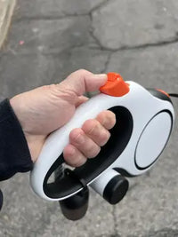 Close-up customer review image showing a hand holding the ergonomic non-slip handle and orange brake button of the retractable dog leash.